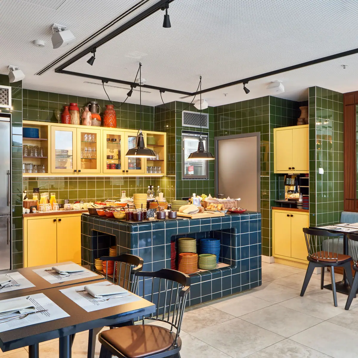 In-house kitchen at HENRI Düsseldorf A restaurant with green tiles and yellow cupboards.