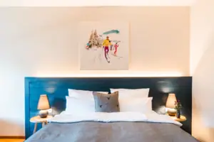 L-Studio Haus Ache HENRI Hotel Kitzbühel A bed with a painting above it.