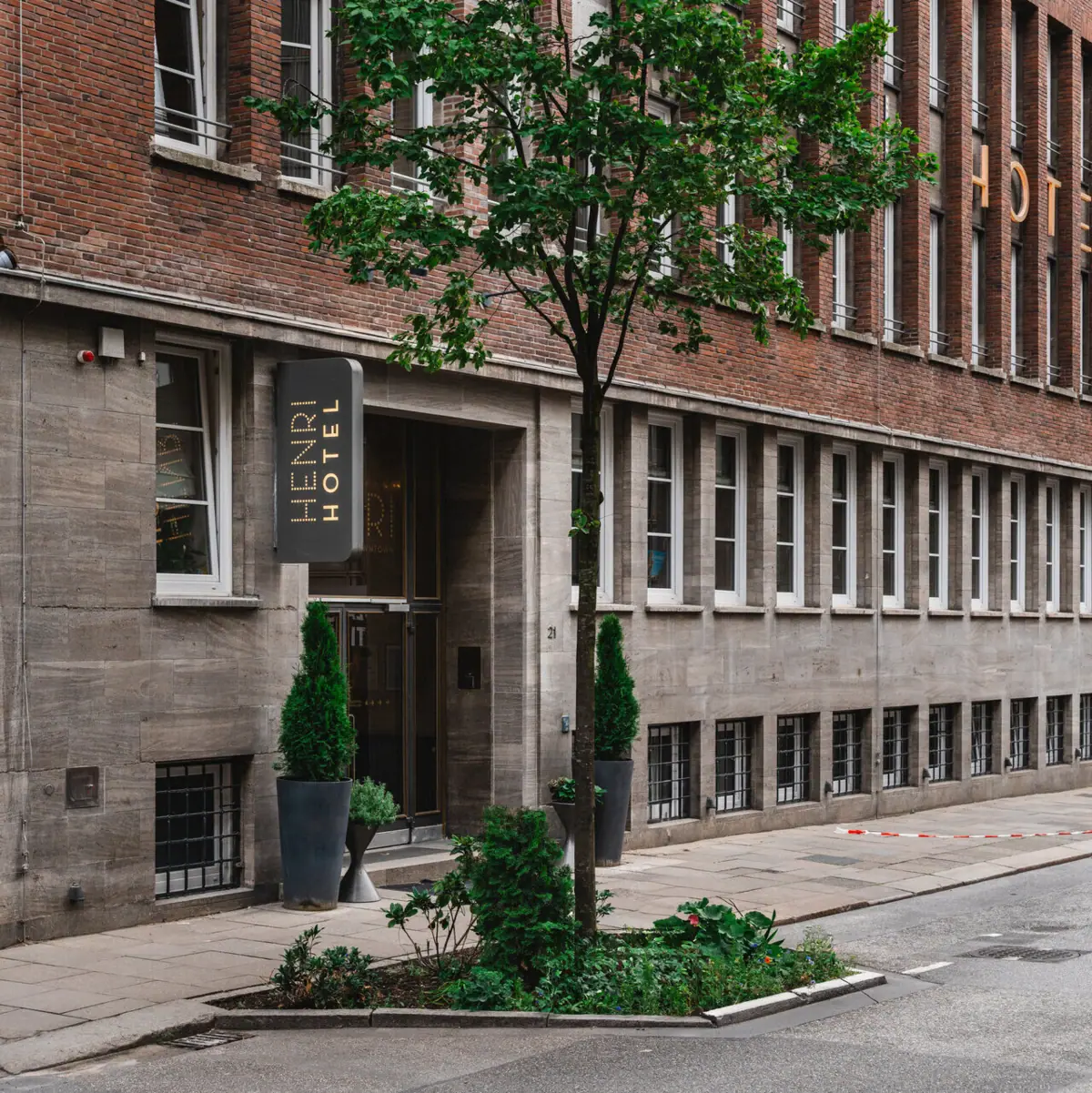 HENRI Hotel Hamburg Entrance A tree next to the entrance to the HENRI Hotel Hamburg.