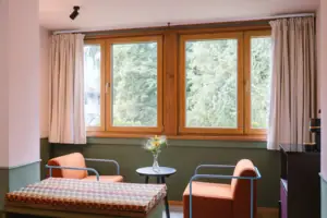 Hotel rooms at the HENRI Hotel Garmisch-Partenkirchen A seating area with two armchairs in front of a window in the Chambre hotel room at the HENRI Hotel Garmisch-Partenkirchen.