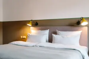 Bed A bed with white cushions and a lamp.