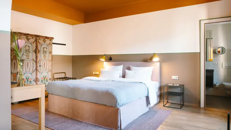 Rooms at the HENRI Hotel Garmisch-Partenkirchen A hotel room at the HENRI Hotel Garmisch-Partenkirchen with a cosy bed and an old wardrobe.