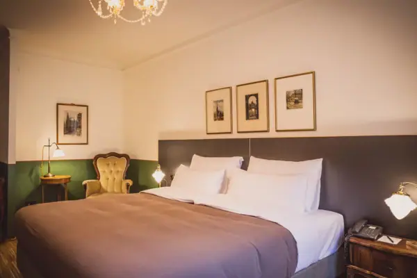 Room A bed with a chandelier and pictures on the wall.