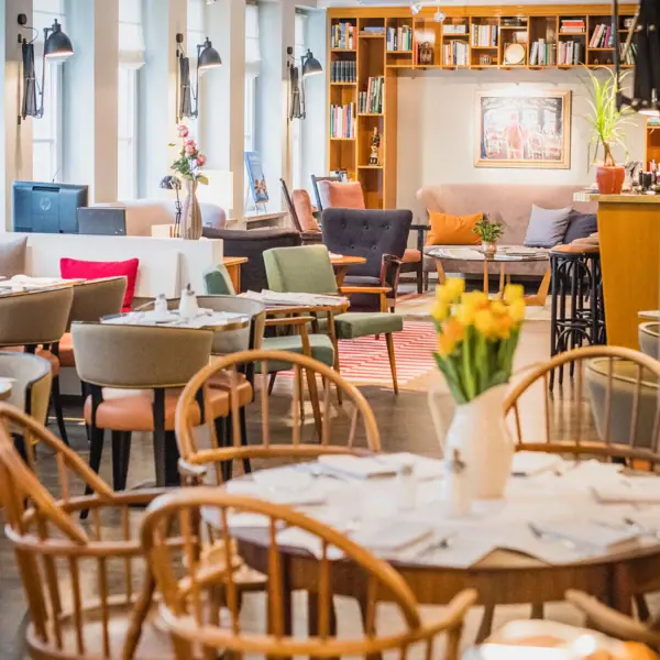 Dining and lounge area at HENRI Hamburg Tables, chairs and a cosy lounge area in the background