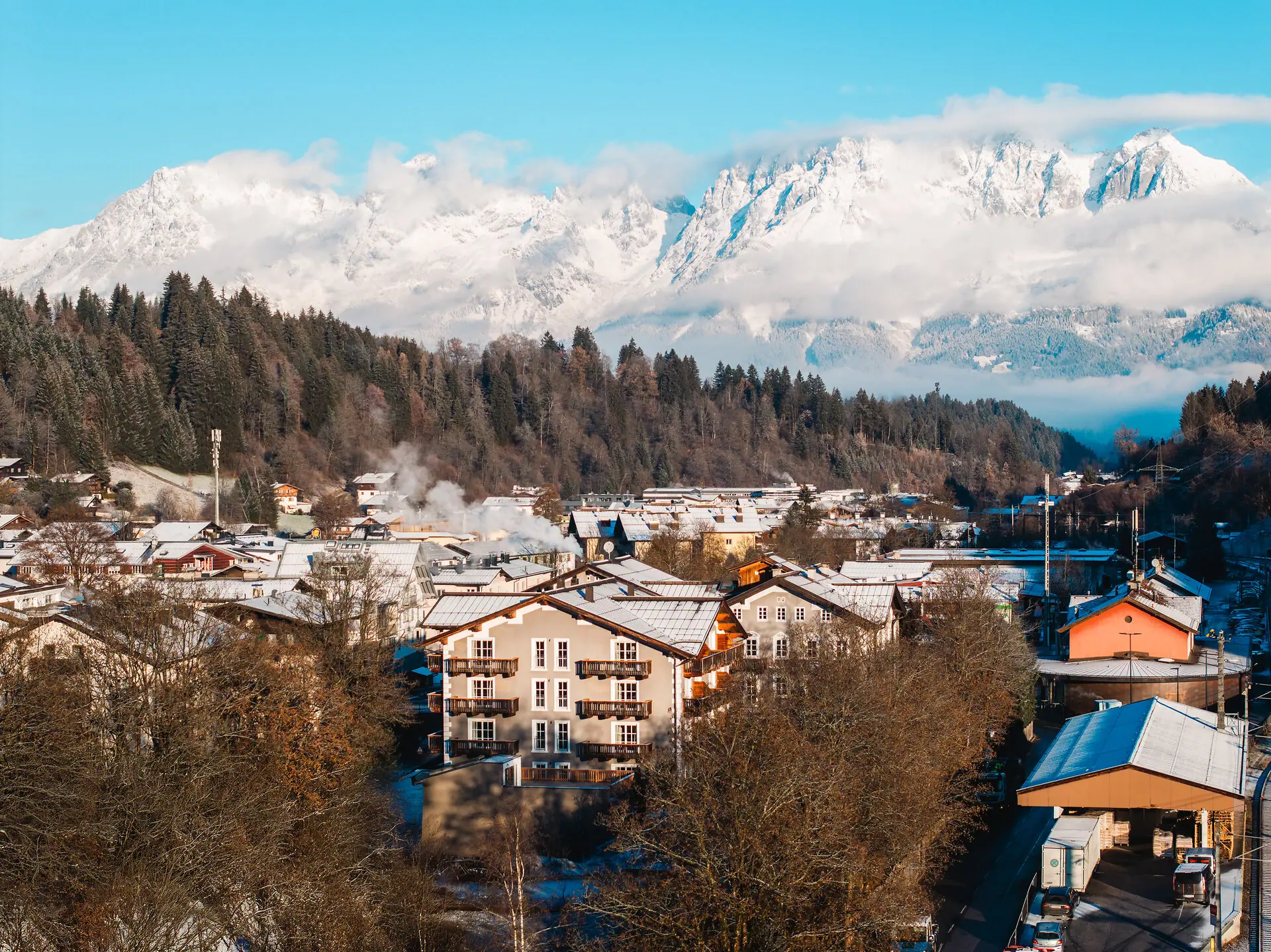 HENRI Kitzbühel: aerial view A mountain village with snow-capped mountains in the background.