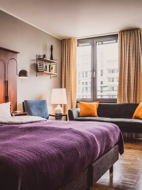 HENRI Düsseldorf Bedroom with purple bed and couch.