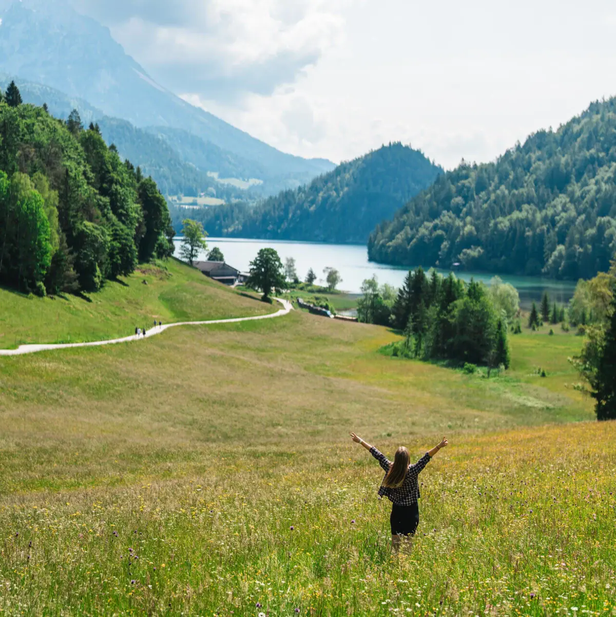 Kitzbühel Alps A woman stands in a field with her arms raised.