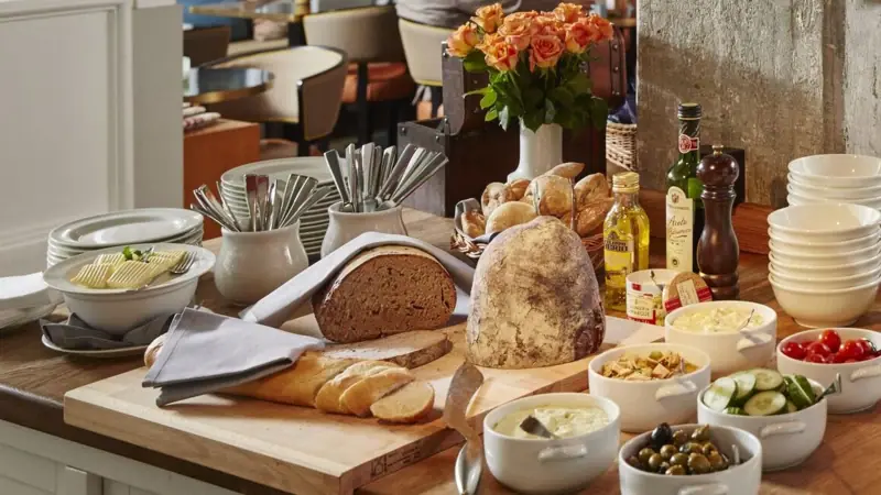 Dinner at HENRI There is a chopping board with bread and a few small bowls of food on a table.