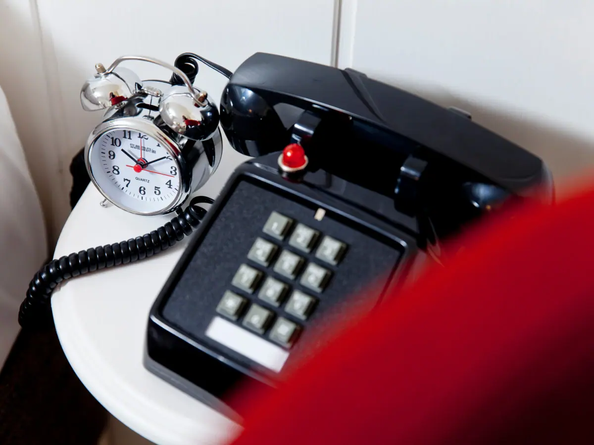 Retro telephone and silver alarm clock Retro telephone and silver alarm clock on a white side table