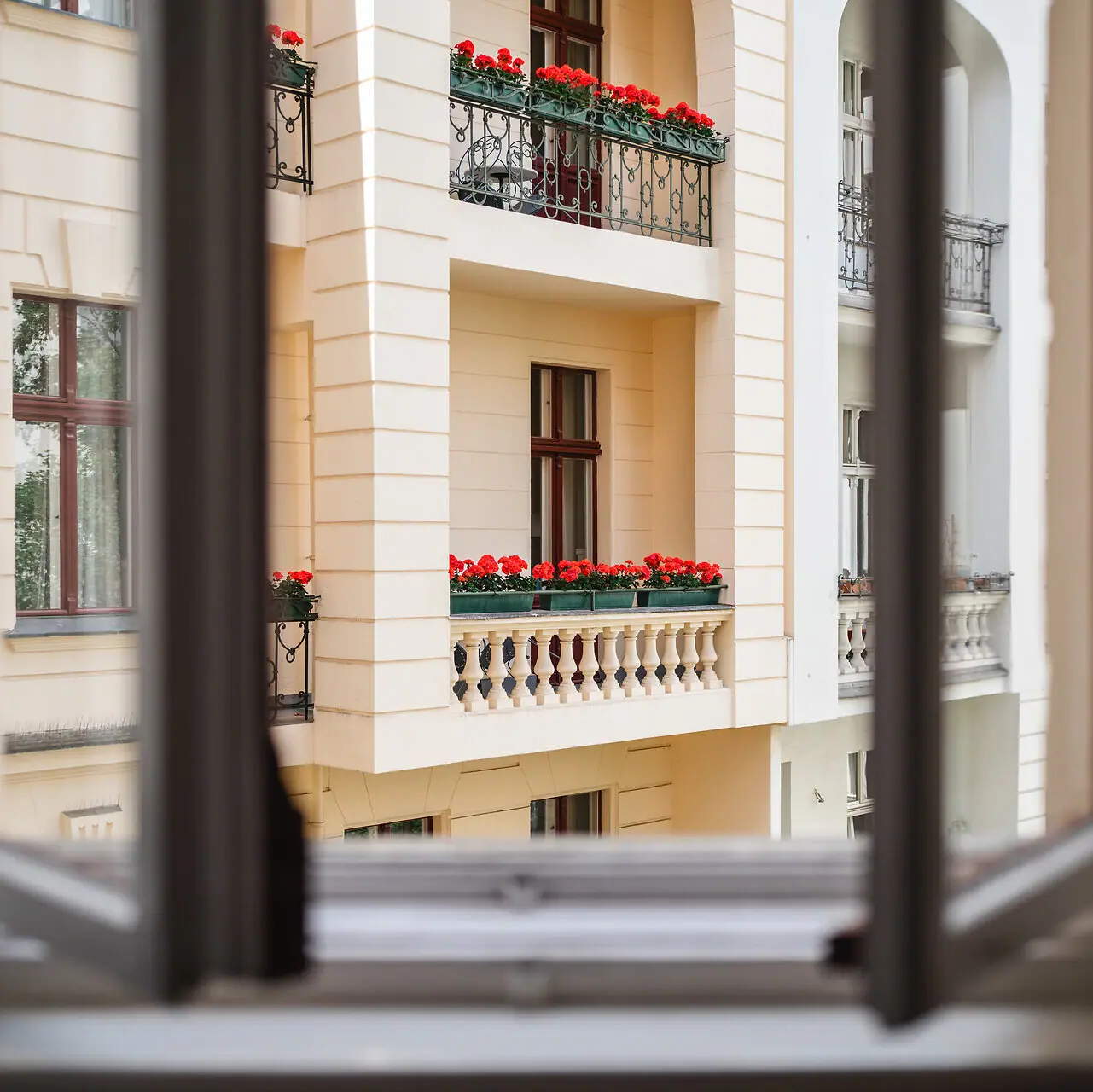 HENRI Berlin Balcony view A window with a view of a building with flowers on the balcony.
