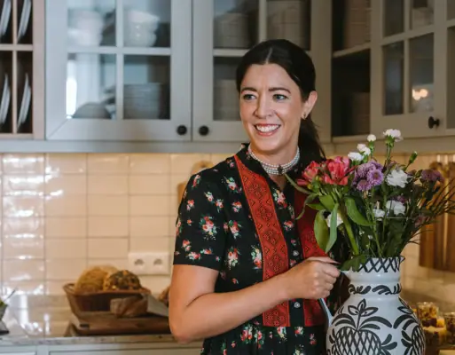 HENRI welcomes you A woman holds a vase of flowers.