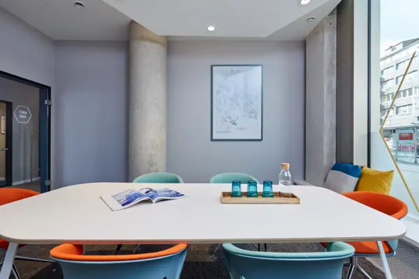 Beehive Düsseldorf A table with blue chairs and a book on it.