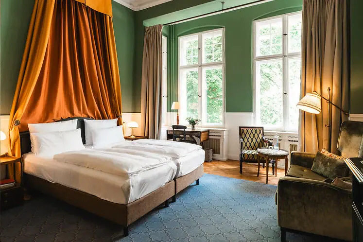 Rooms at the HENRI Hotel Berlin A room with two beds and a sofa.