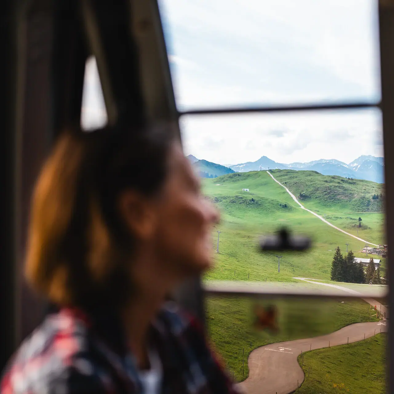 A woman looks out of a window at a landscape.