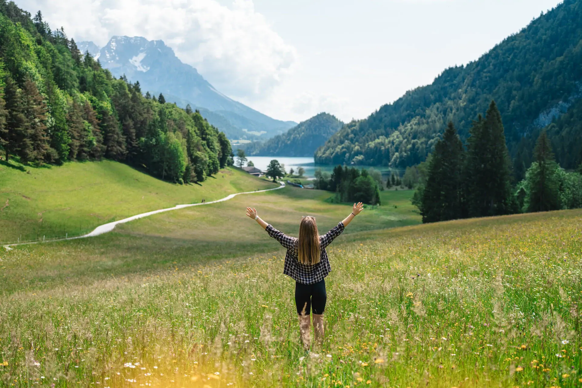Kitzbühler Alpen Eine Frau steht in einem Feld mit erhobenen Armen.