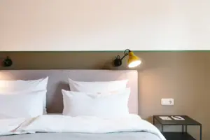 Hotel rooms at the HENRI Hotel Garmisch-Partenkirchen A bed with white pillows in front of a two-coloured wall in the HENRI Hotel Garmisch-Partenkirchen.