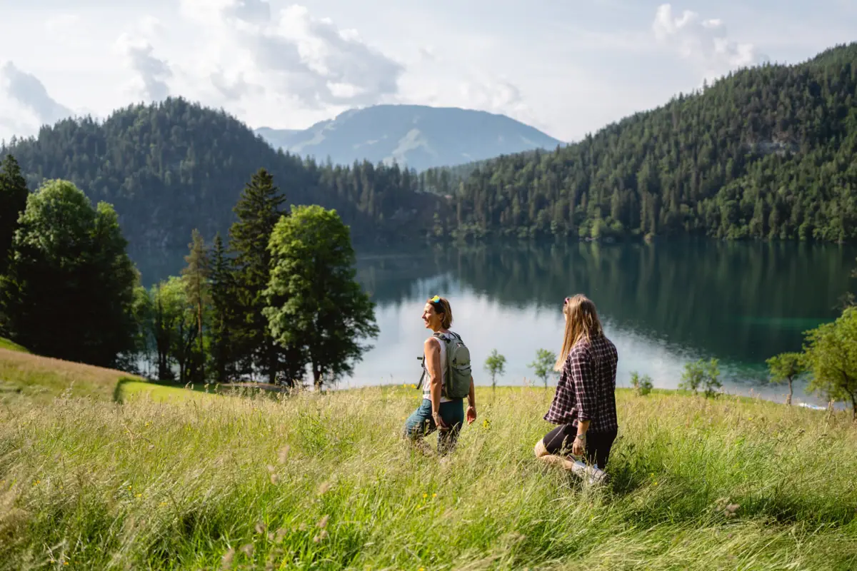 Hike along the lake Two people are standing in a grassy field by a lake.