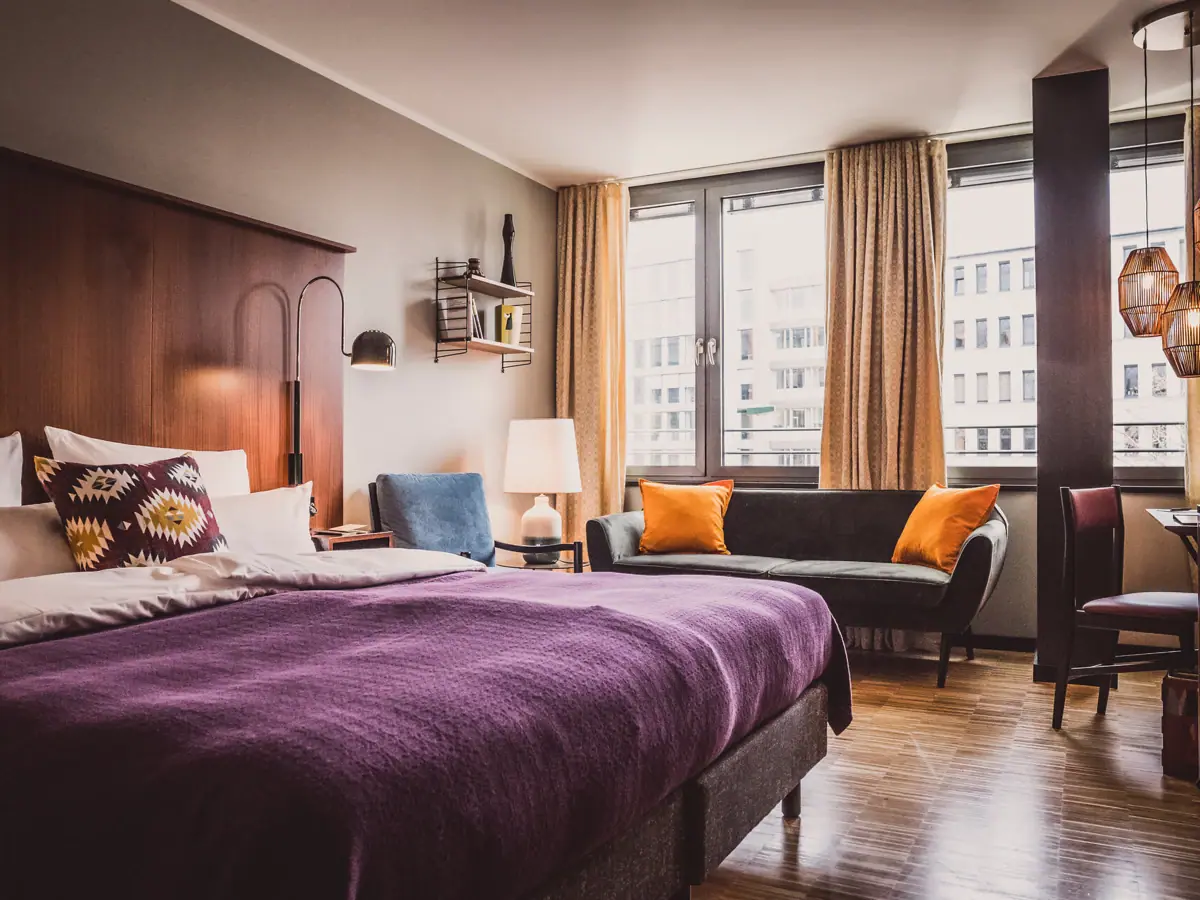 HENRI Düsseldorf Bedroom with purple bed and couch.