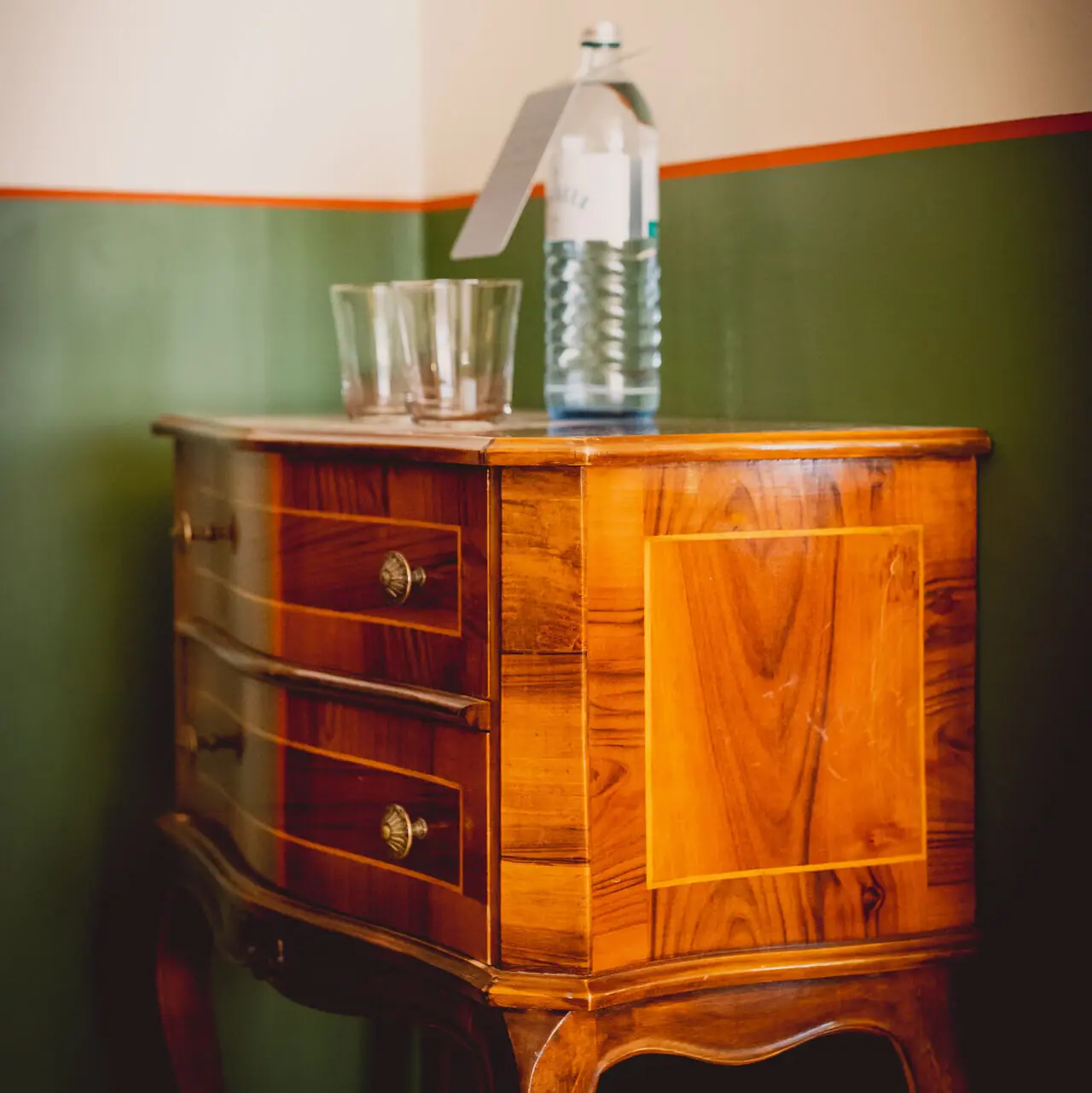 Chest of drawers Wooden chest of drawers with a water bottle on it