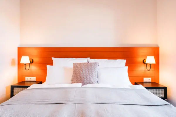 Bed A bed with pillows and a lamp on the bedside table.